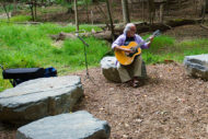 Man playing guitar on Green Road wild garden at Walter Reed Medical Center