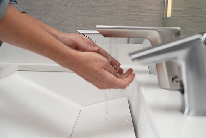 Woman washing hands at automatic handwash sink