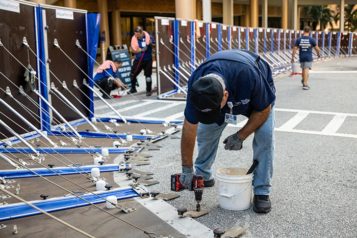 Tampa General Hospital facilities staff anchor the AquaFence into the concrete along the hospital’s perimeter in preparation for hurricane season