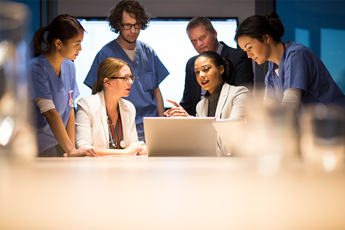 Six hospital staff gathered around a computer 