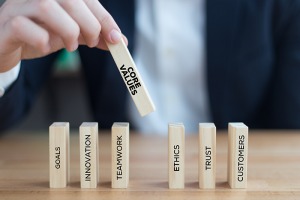 Hand stacking blocks that say goals, innovation, teamwork, core values, ethics, trust and customers