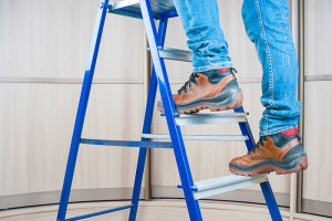 Maintenance worker stepping on ladder